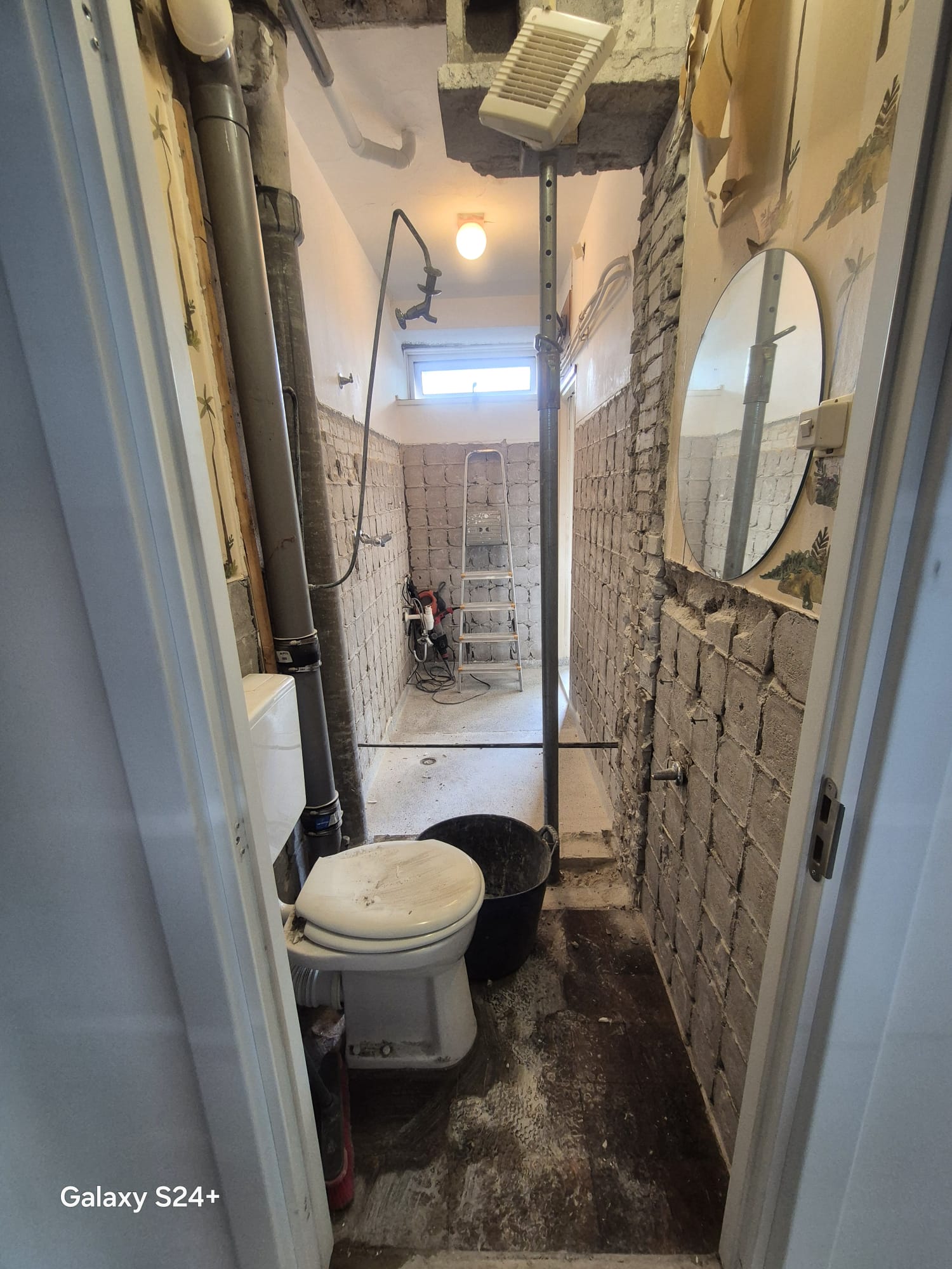 Gestripte natte cel met oud toilet en kaal metselwerk