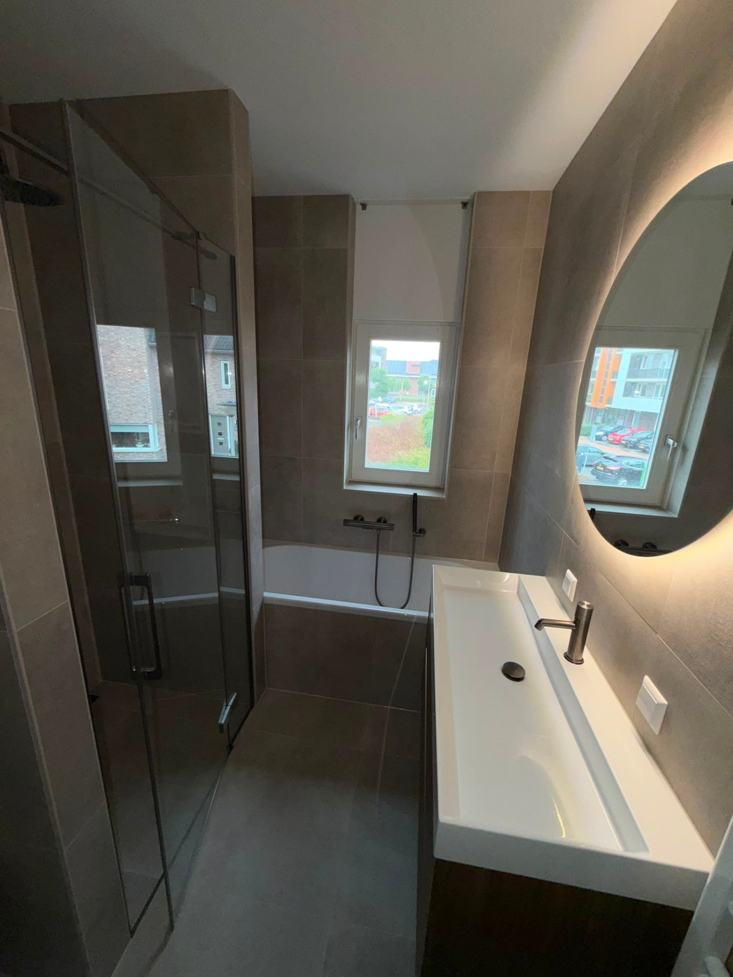 Overzicht van de nieuwe badkamer met ronde spiegel en brede wastafel