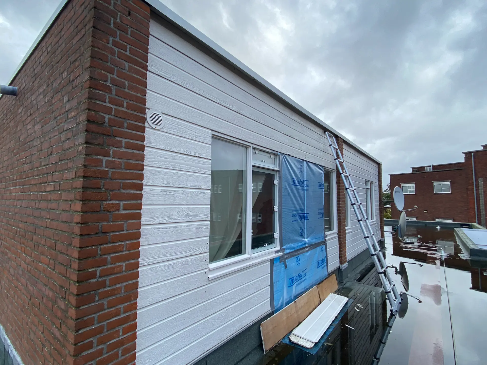 Nieuwe gevelbeplating met dampopen folie tijdens de montage