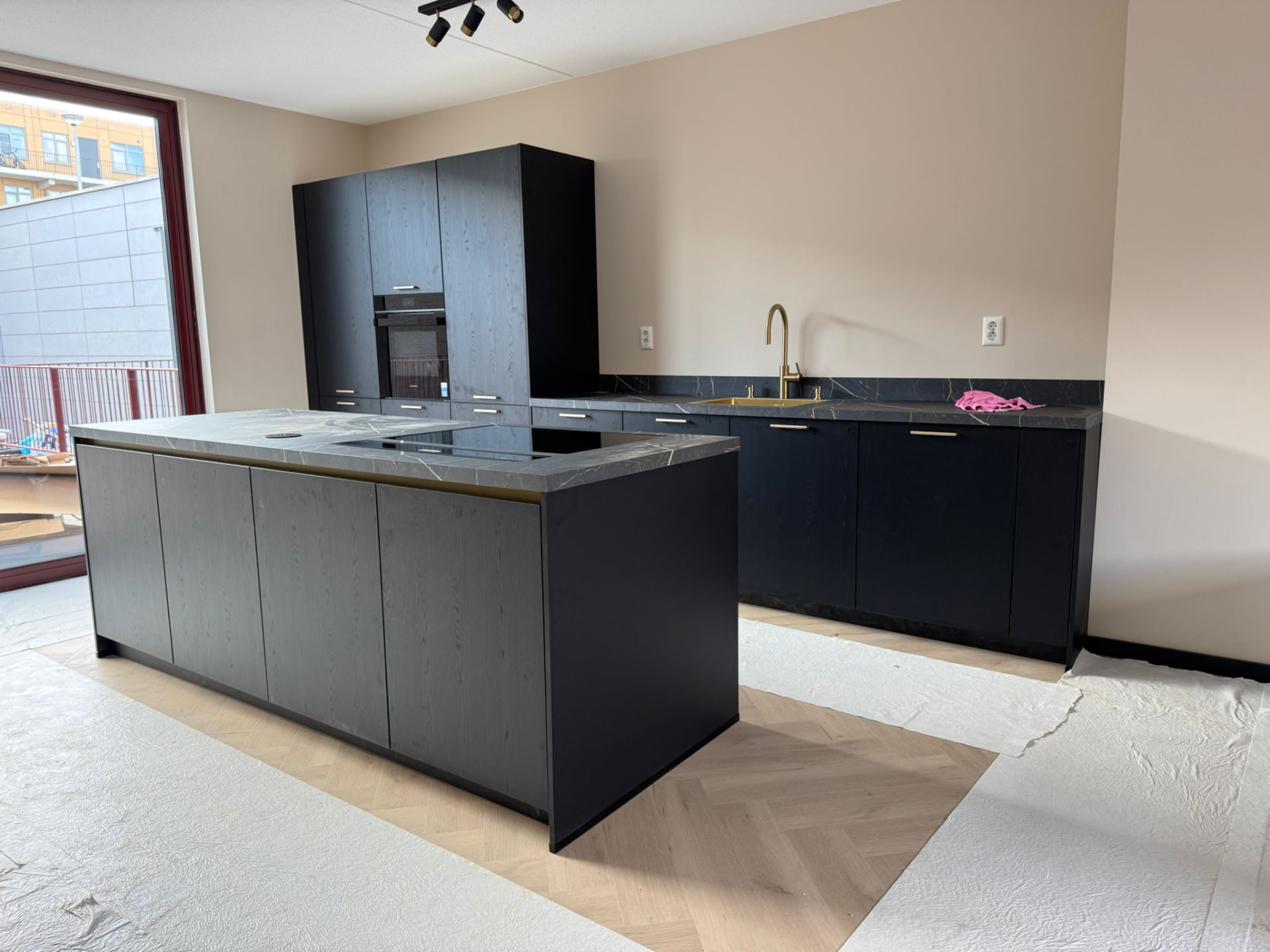 Zwarte keuken met kookeiland en marmerlook blad