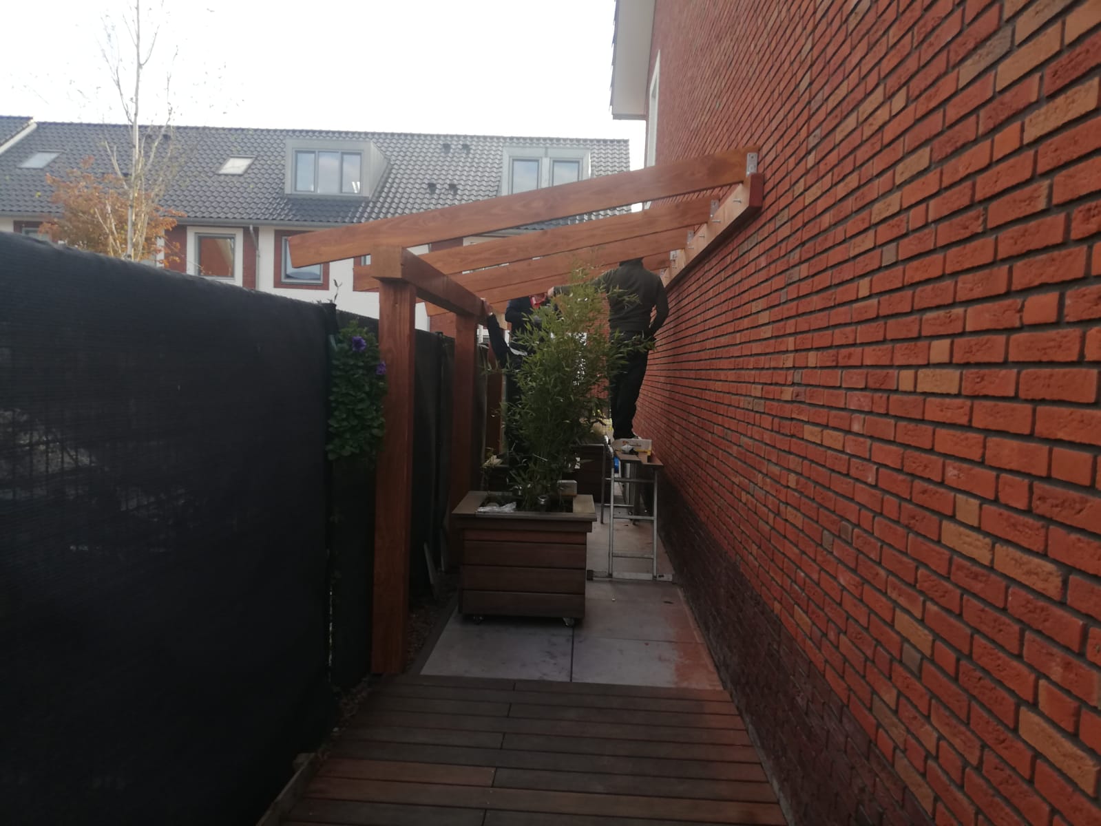 Plaatsing van de houten overkapping tegen de gevel