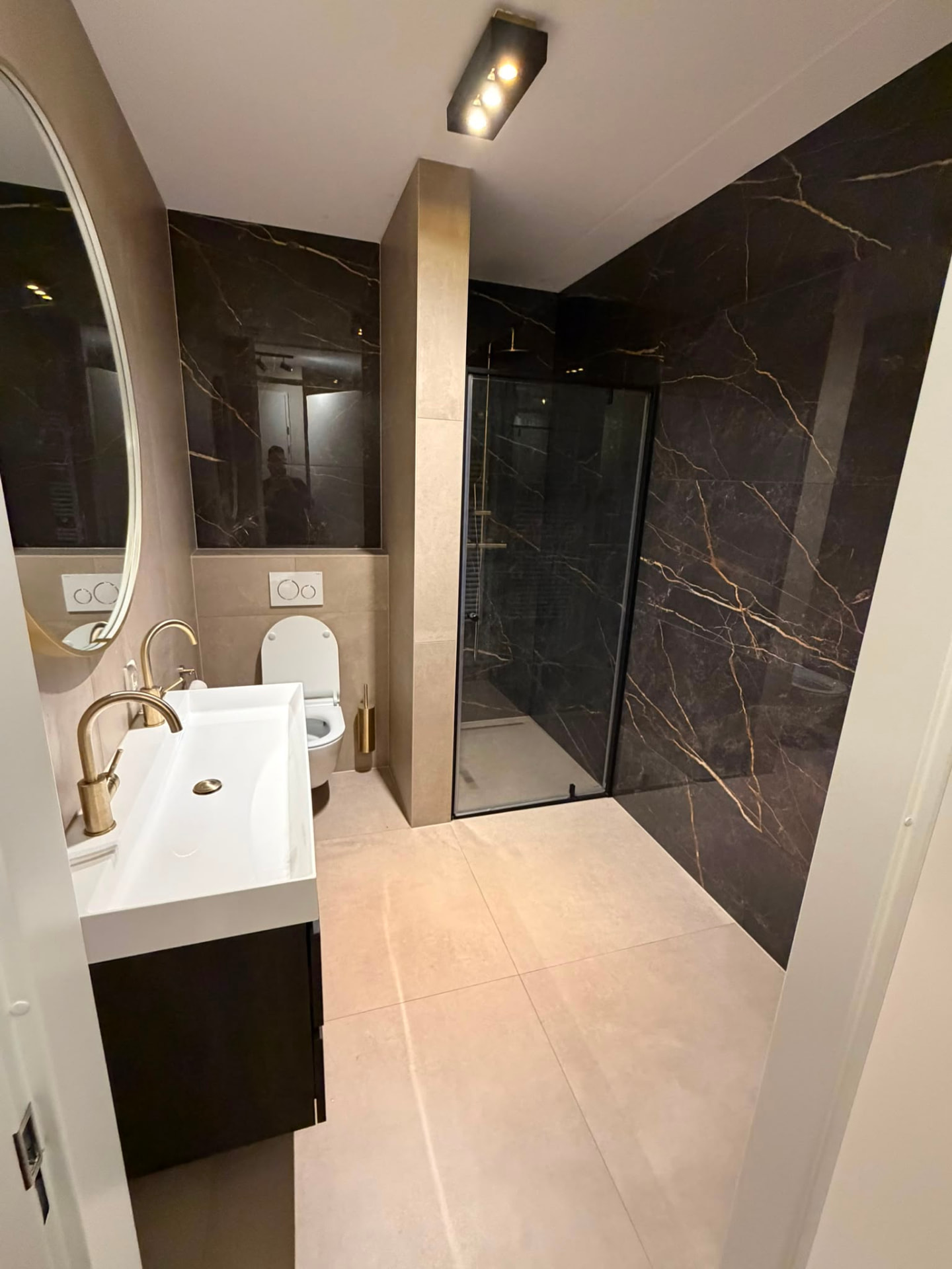 Badkamer met wastafel, toilet en inloopdouche in marmerlook